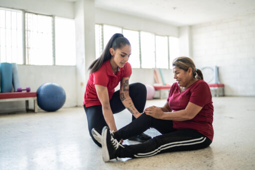 Senior woman being helped by fitness instructor about pain on her knee
